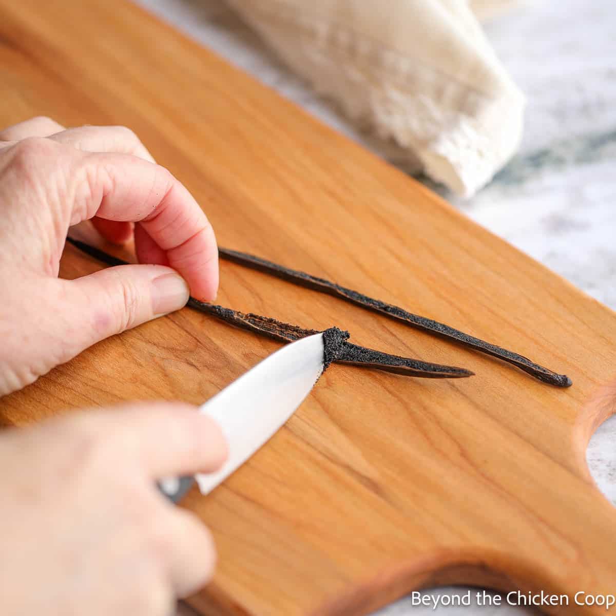 Scraping a vanilla bean with a small knife. 