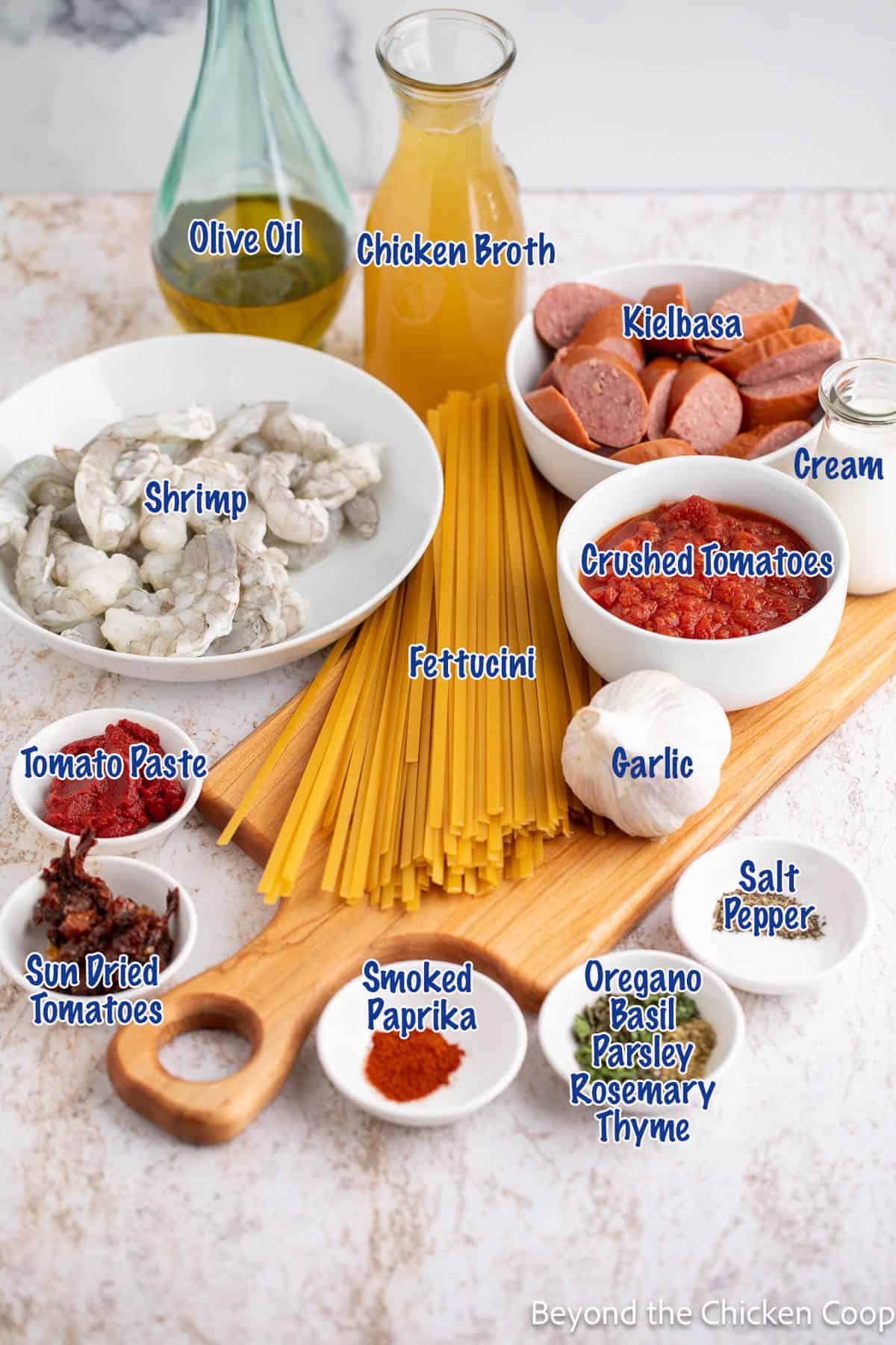 Dried pasta, shrimp, sausage and other ingredients on a board. 