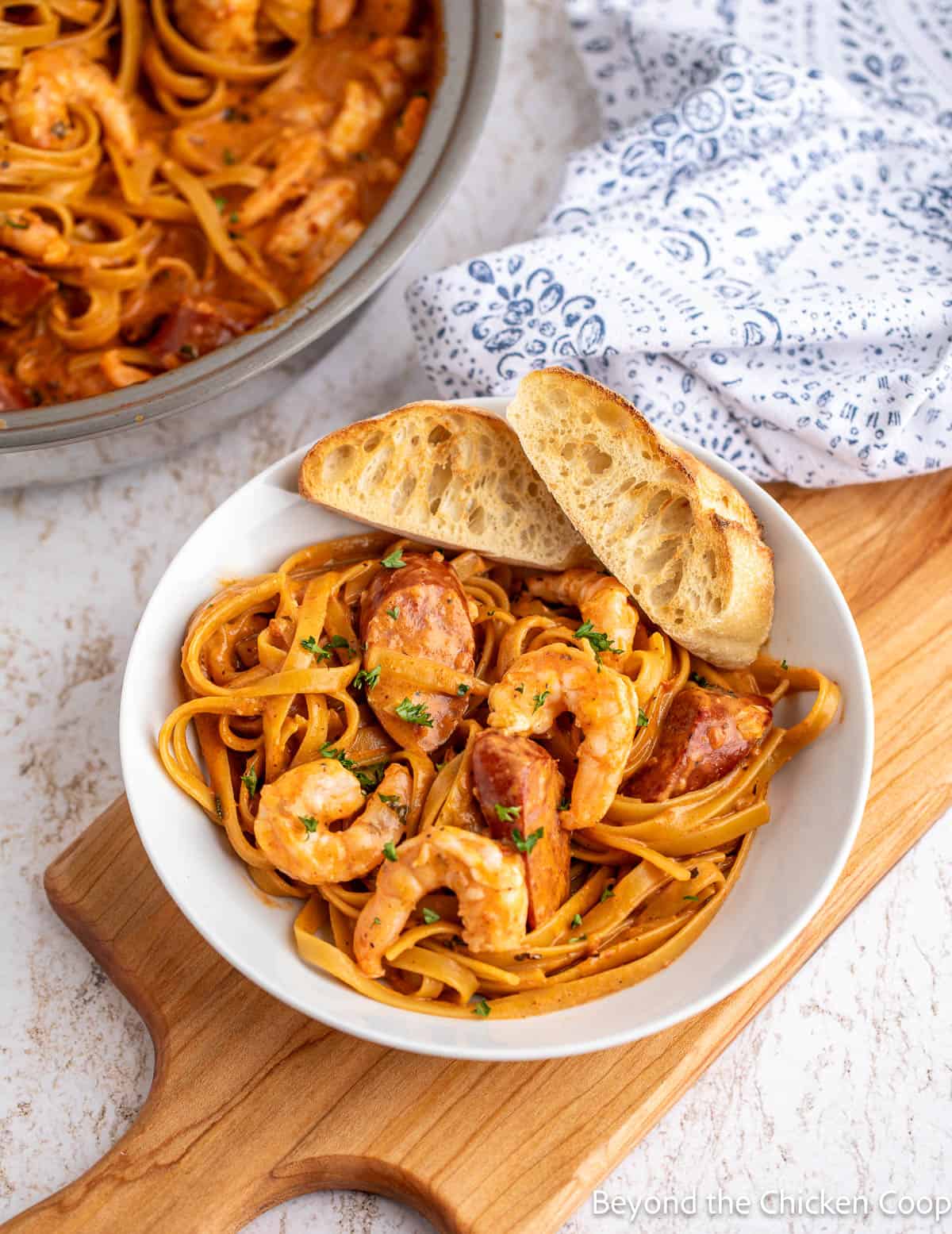 A bowl filled with fettuccine, shrimp, and sausage. 