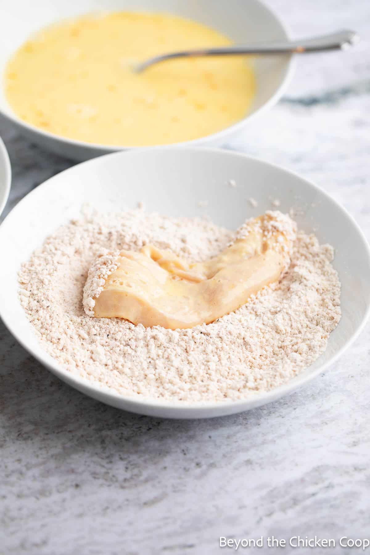 Battering a chicken tender in a panko and flour blend. 