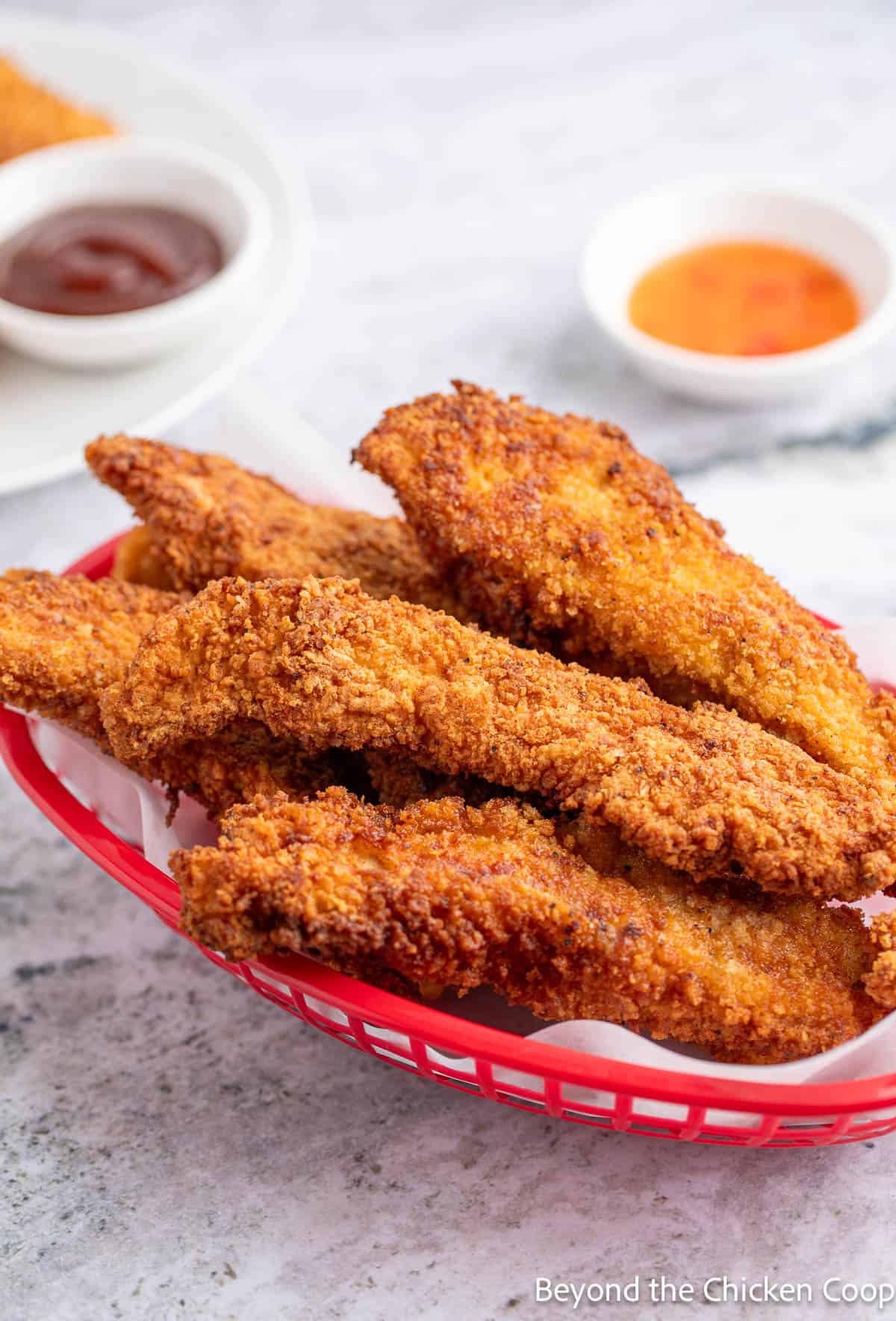 Fried chicken strips in a red basket. 