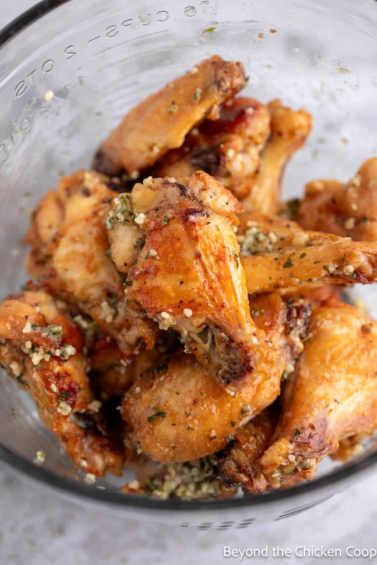 Tossing butter covered wings in a bowl.