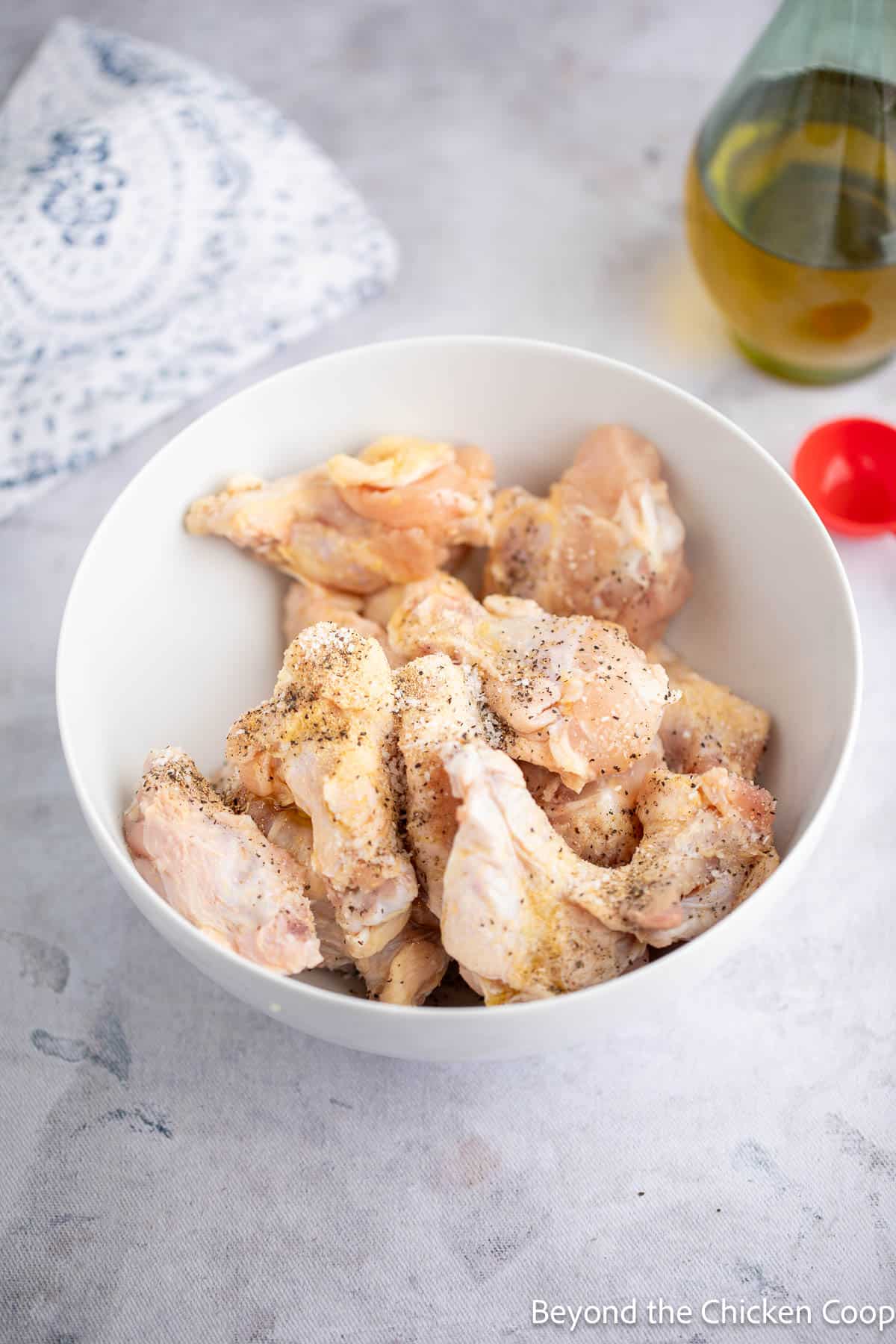 Wings in a bowl with oil and seasonings.