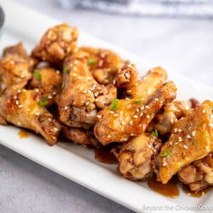 Baked honey garlic wings on a white platter.