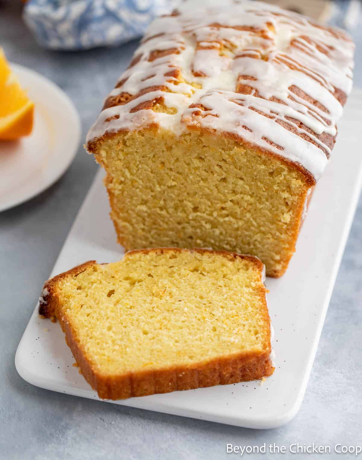 A slice of pound cake with an orange glaze on a platter. 