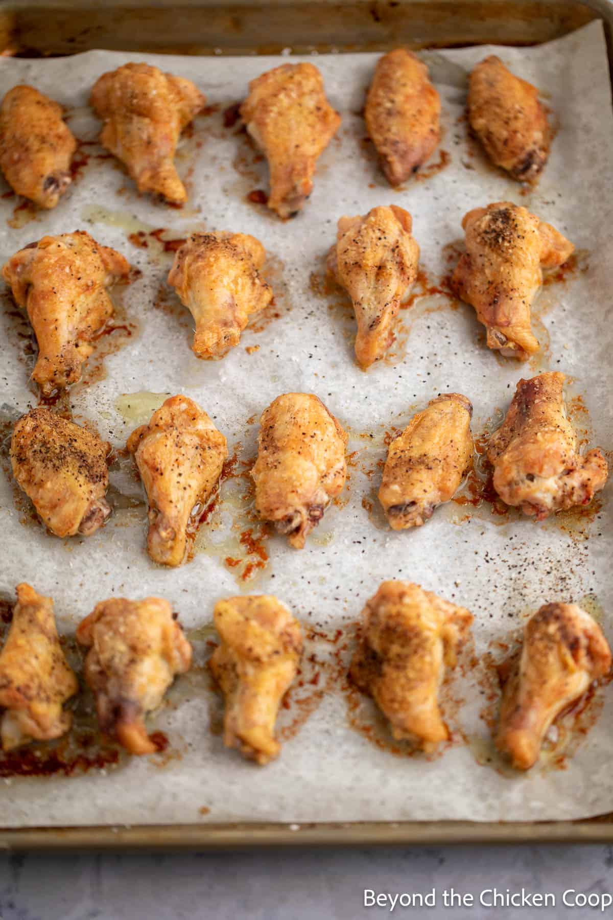 Baked wings on a parchment-lined baking sheet.