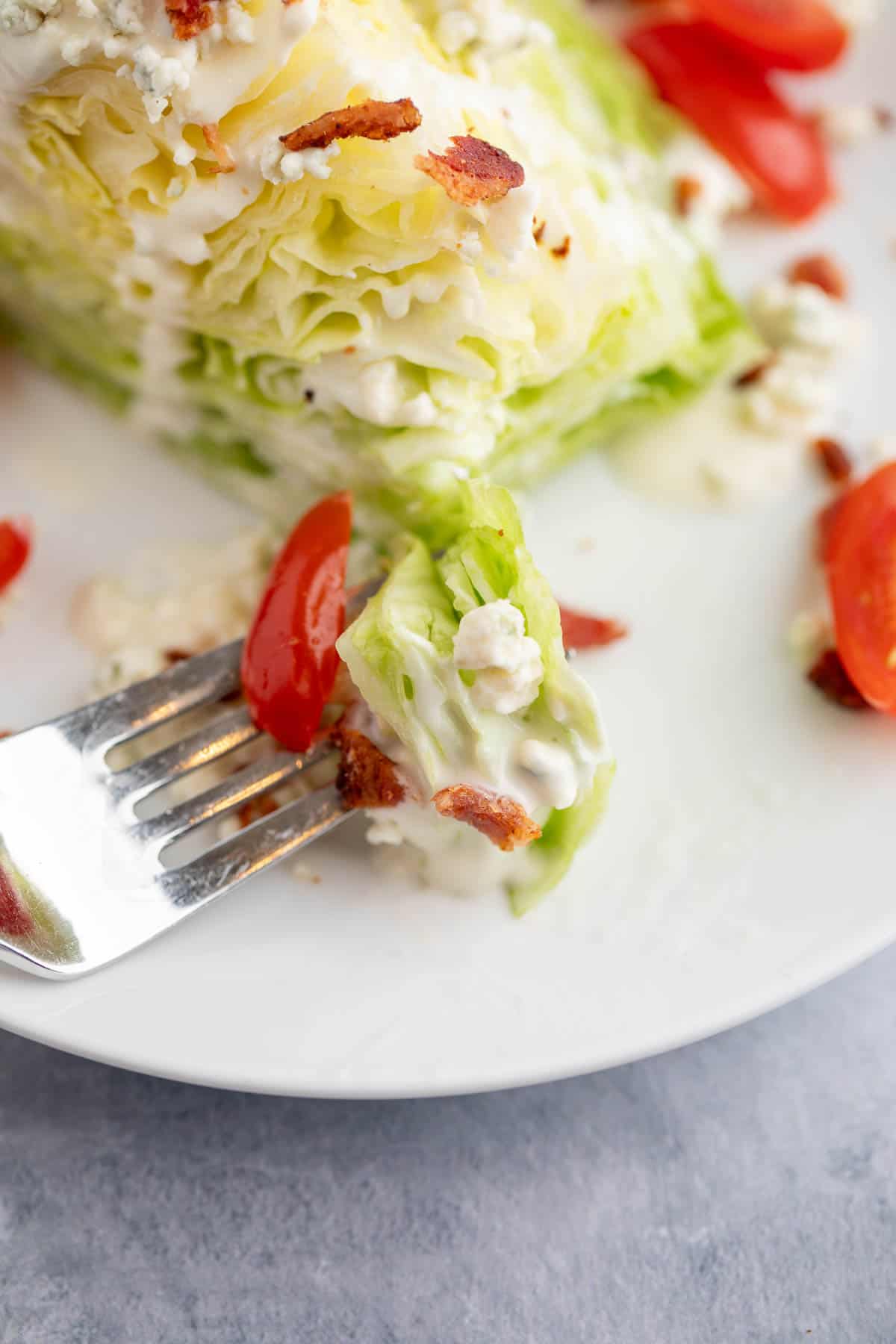 A bite of salad with tomatoes and bacon on a fork. 