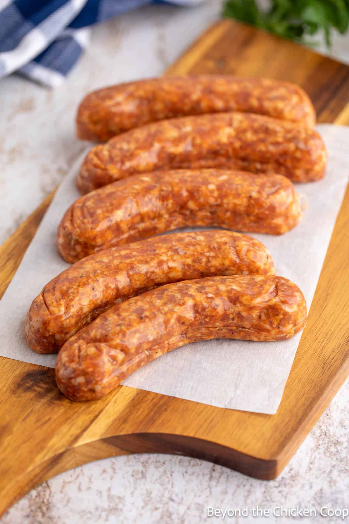 Five uncooked sausages on a board. 