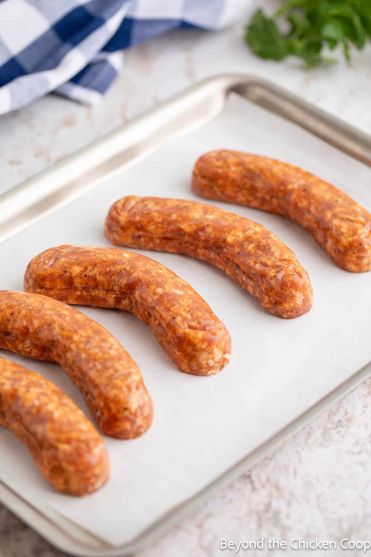 Unbaked sausage links on a baking sheet. 
