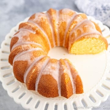 A lemon bundt cake on a white cake plate.