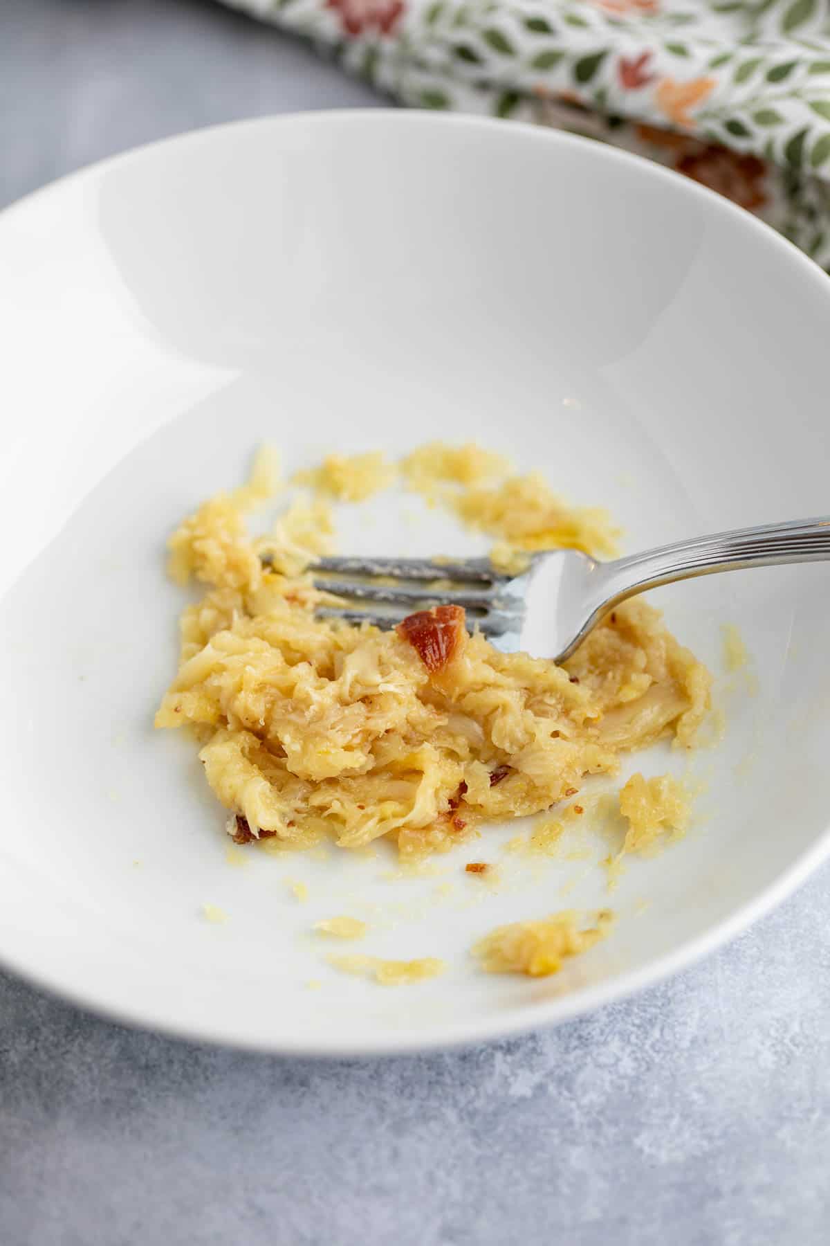 Mashing roasted garlic with a fork.