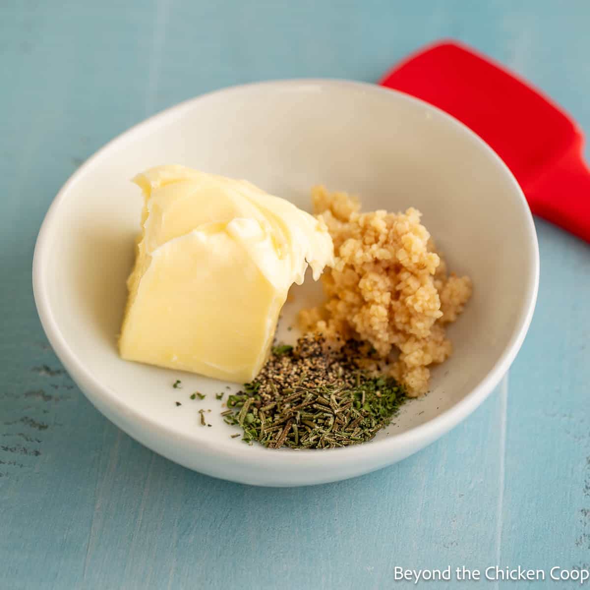 Butter, garlic and herbs in a small white bowl. 