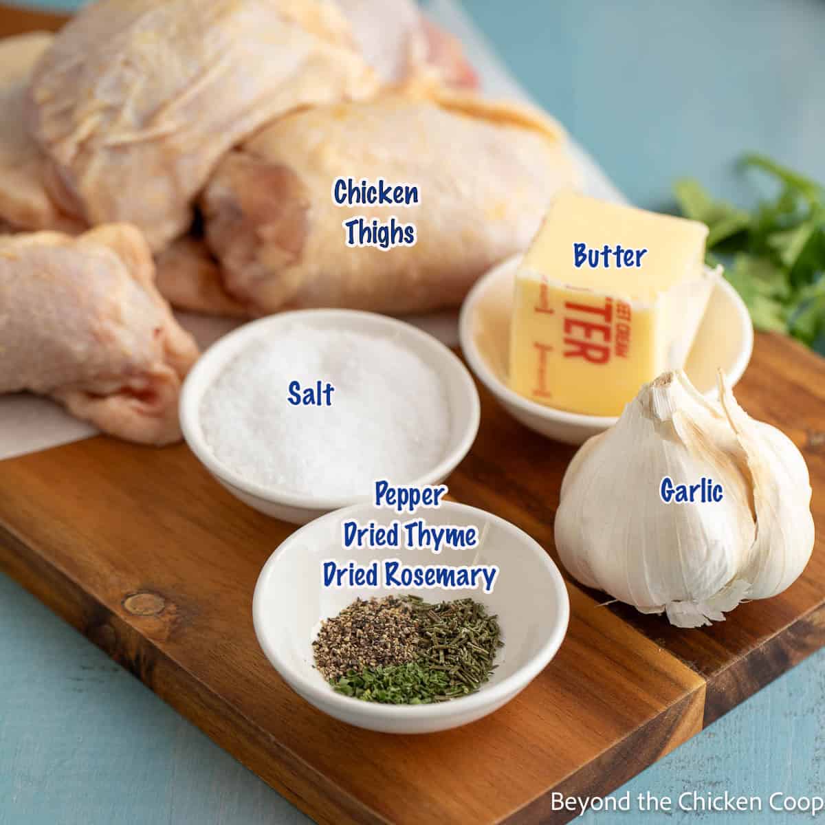 Ingredients in small dishes next to uncooked chicken. 