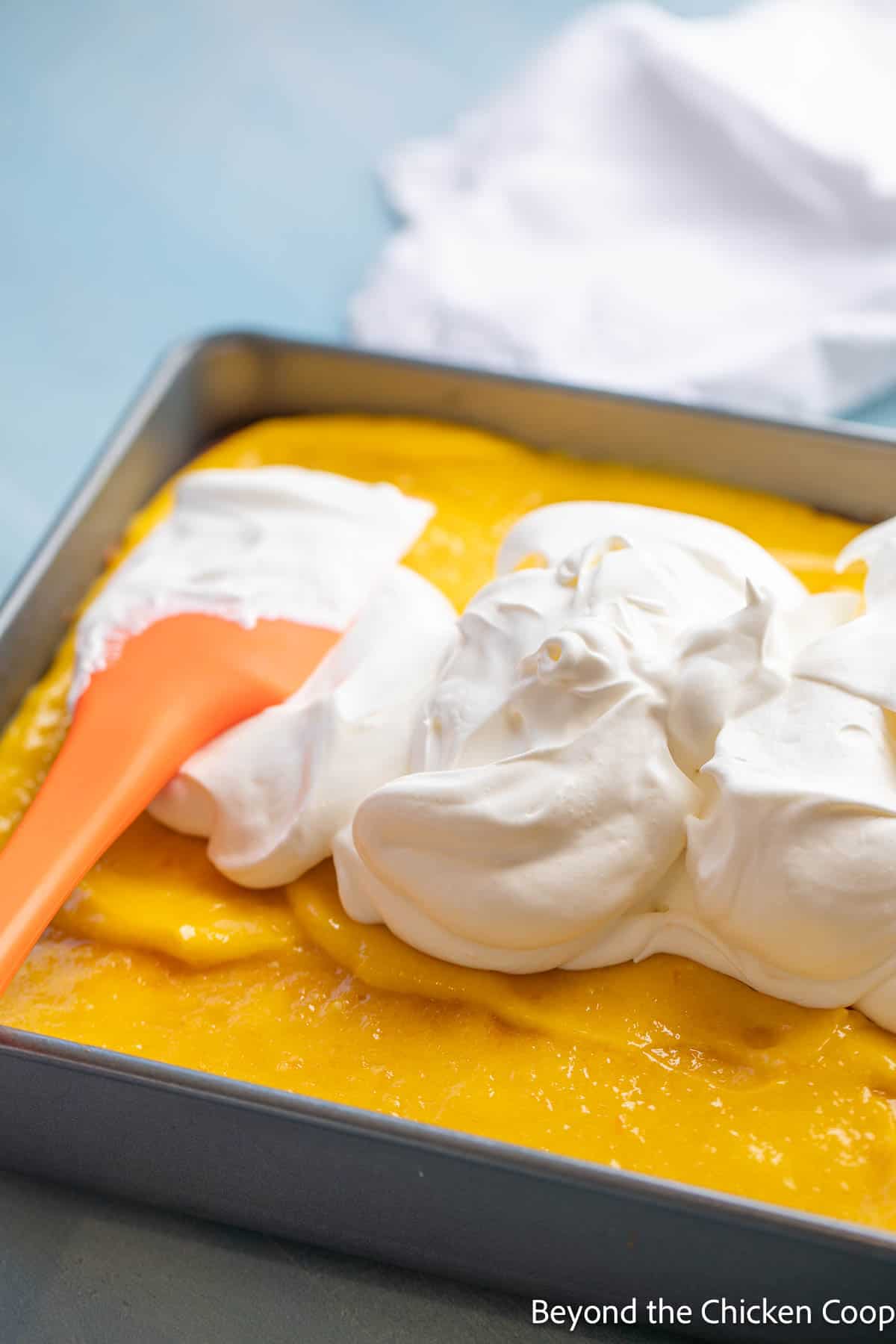 Adding whipped cream to a poke cake. 