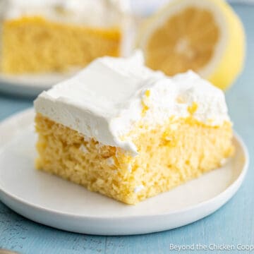 A slice of lemon poke cake on a small white plate.
