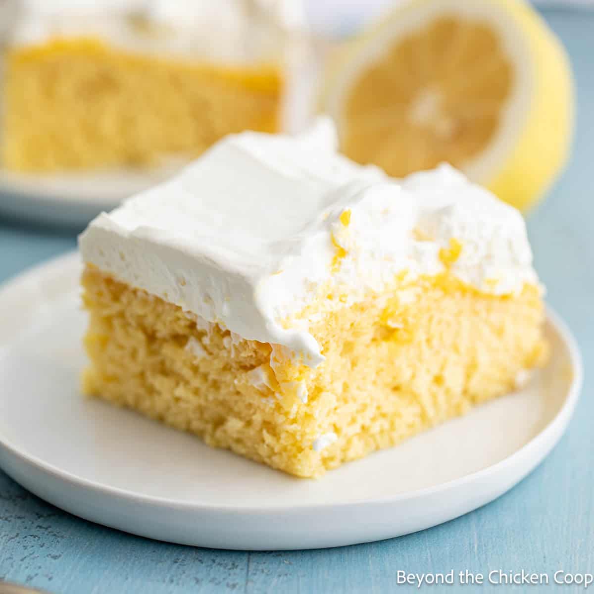 A slice of lemon poke cake on a small white plate. 