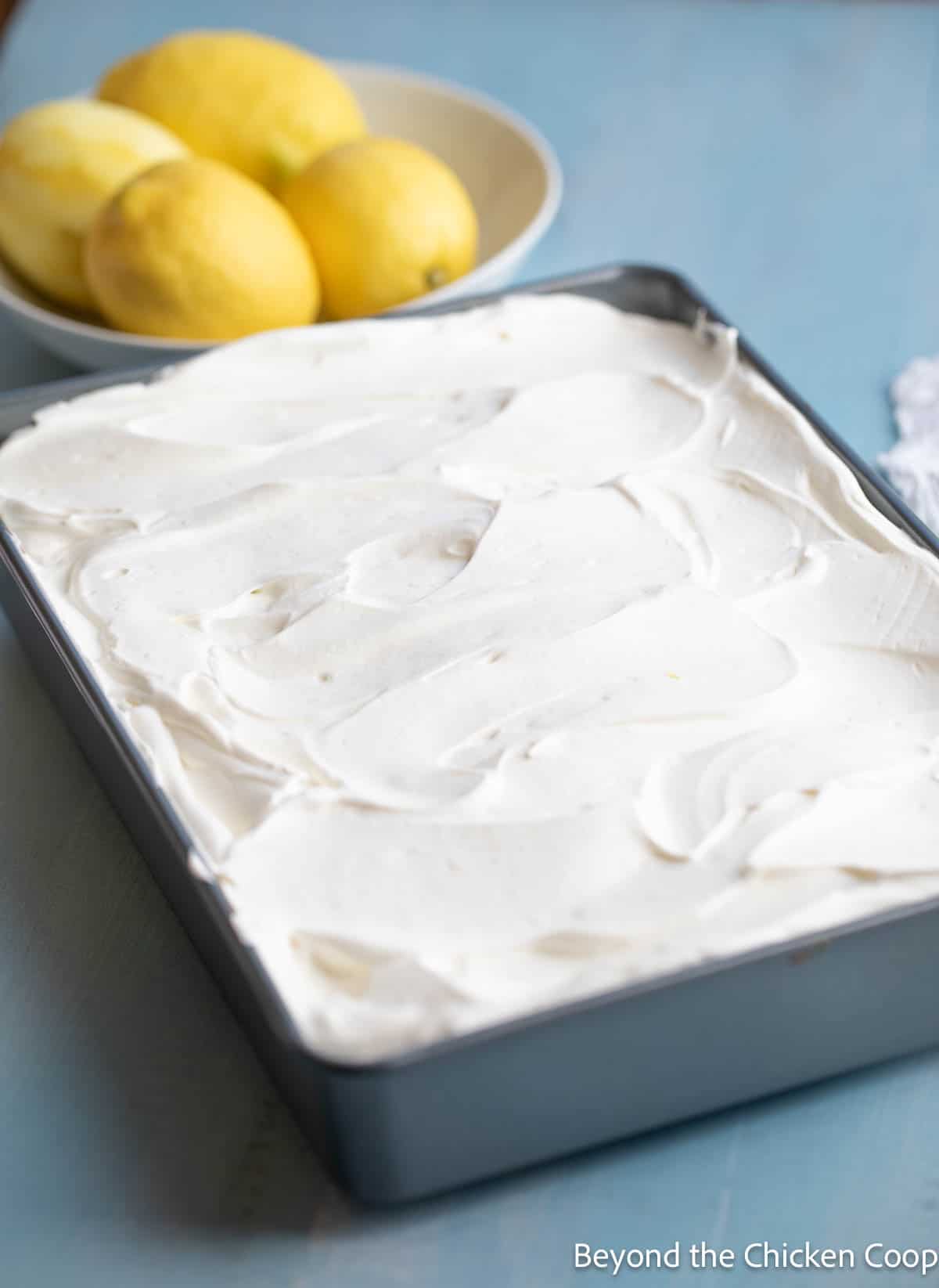 A lemon poke cake topped with whipped cream. 