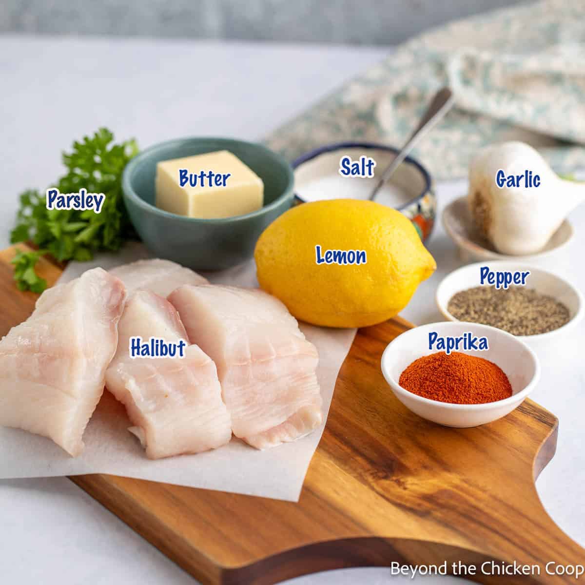 Fish fillets, butter, lemon and seasonings on a wooden board. 