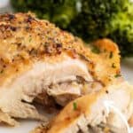 Garlic butter chicken thigh cut on a plate with broccoli.