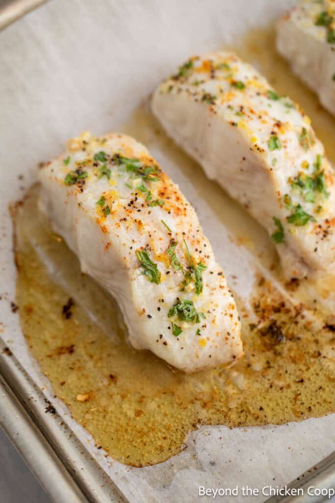 Baked halibut on a baking sheet with melted butter. 