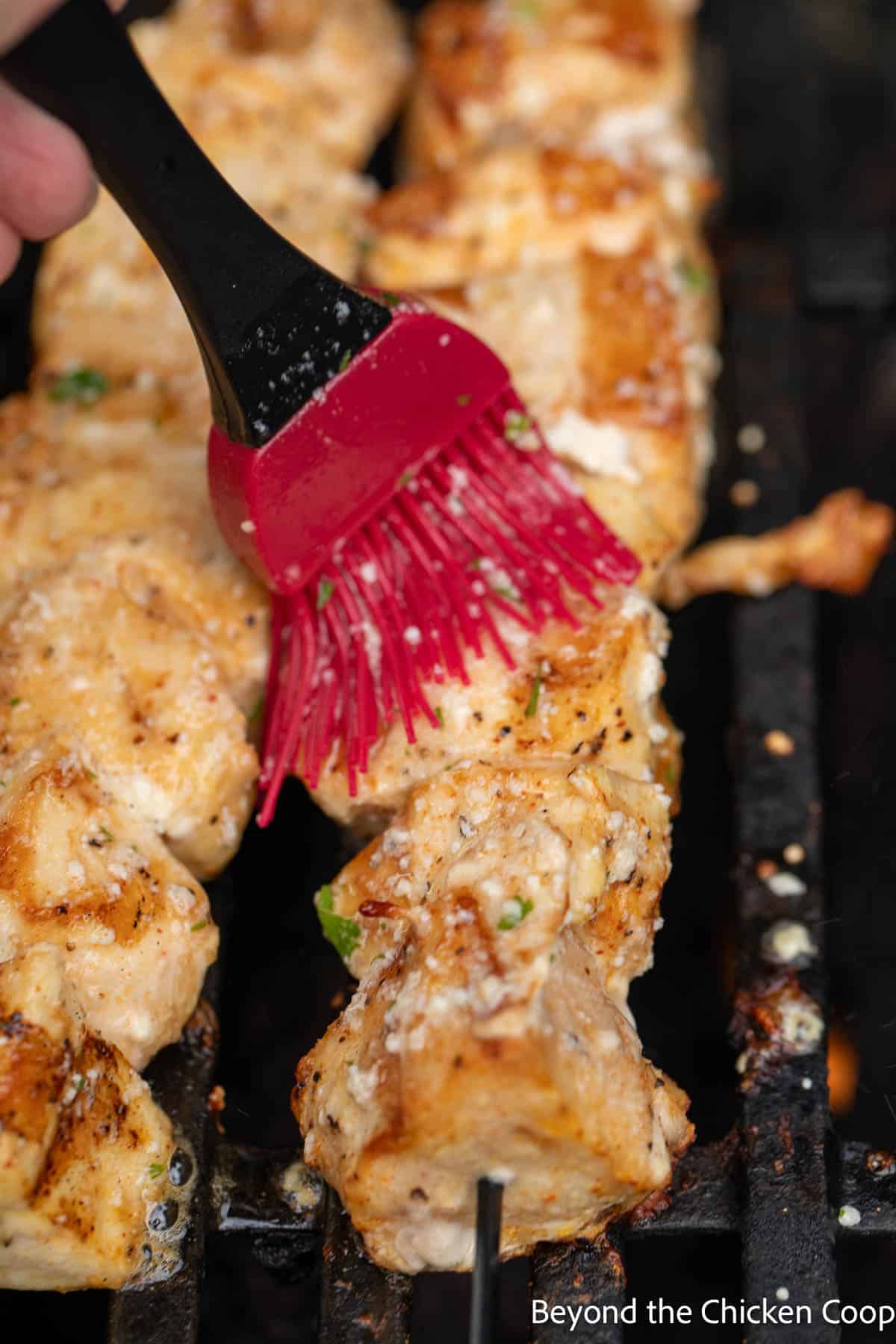 Brushing garlic butter on chicken skewers. 