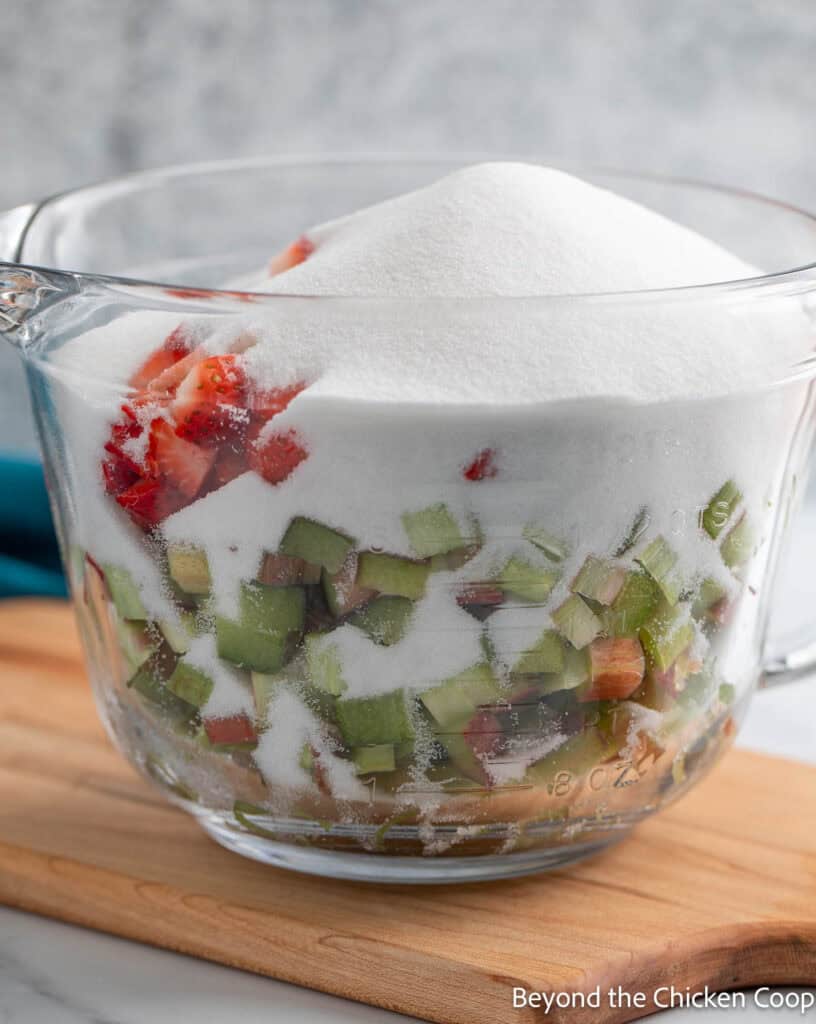A glass bowl with fruit and a pile of sugar. 