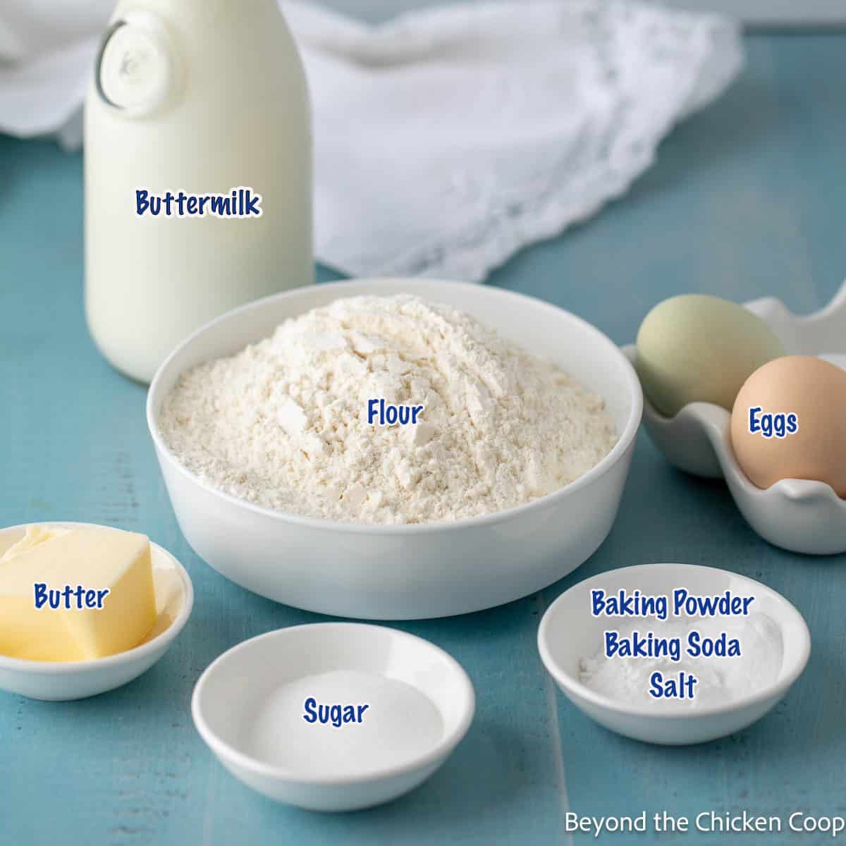 Flour, sugar, eggs, butter and buttermilk in small bowls and containers.