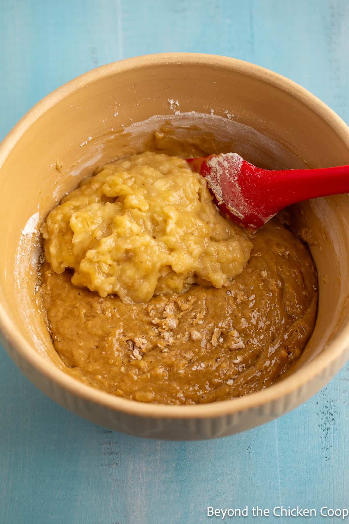 Adding mashed bananas to muffin batter. 