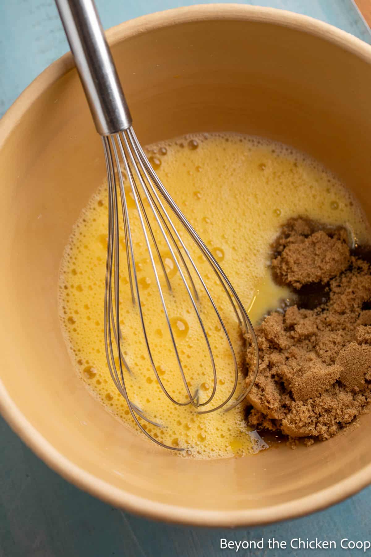 Mixing eggs with brown sugar in a bowl. 