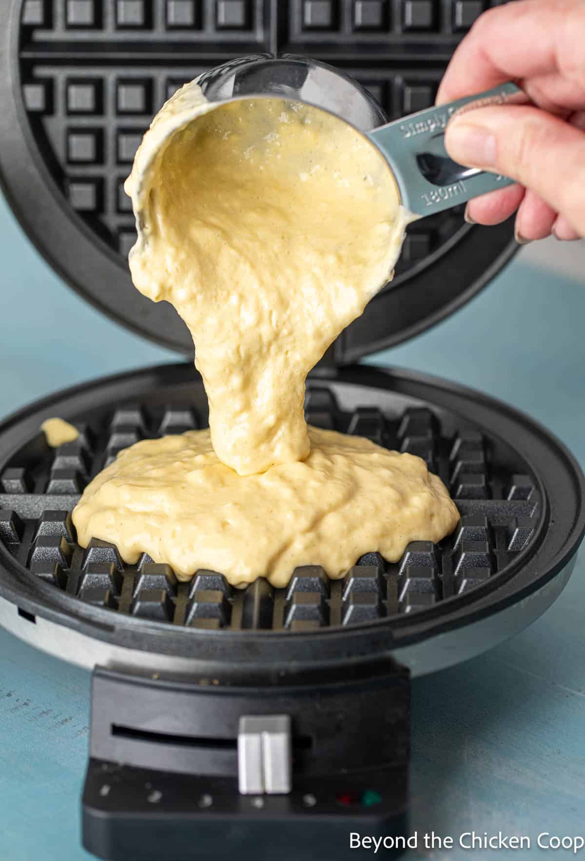Pouring batter onto a hot waffle iron.