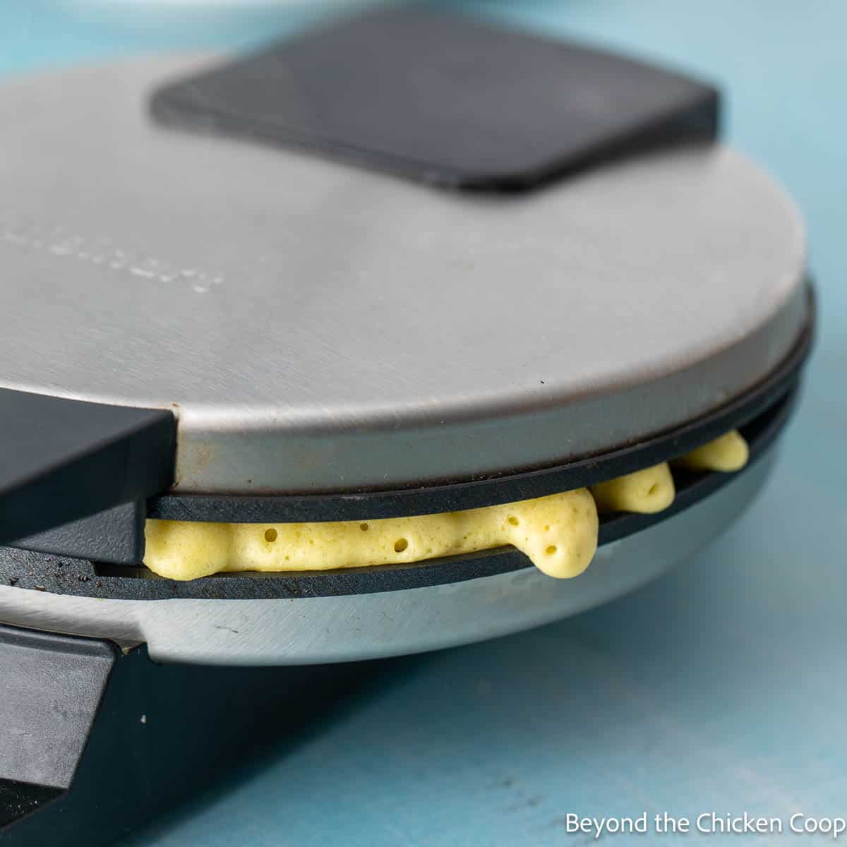 Waffle batter peeking out from a waffle iron.