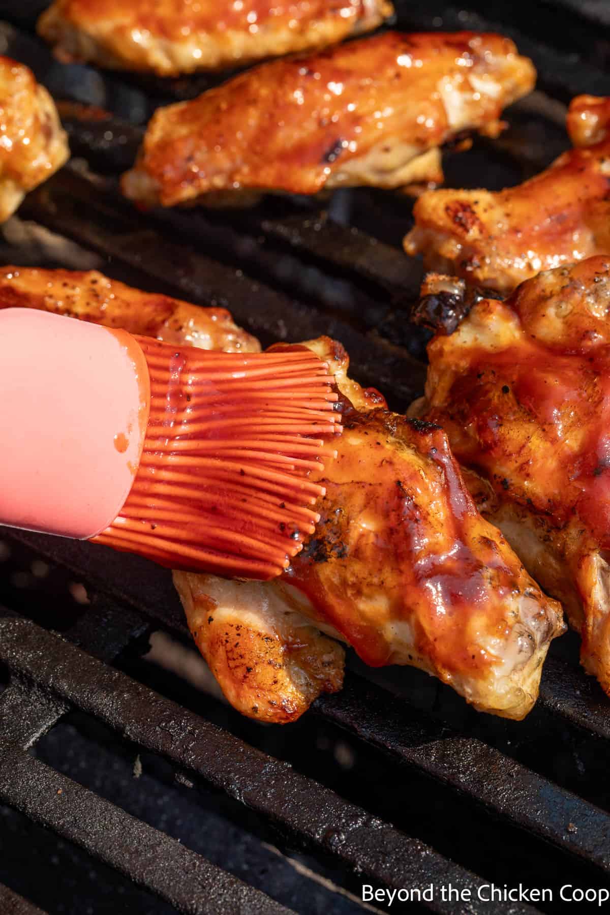 Brushing BBQ sauce over wings. 