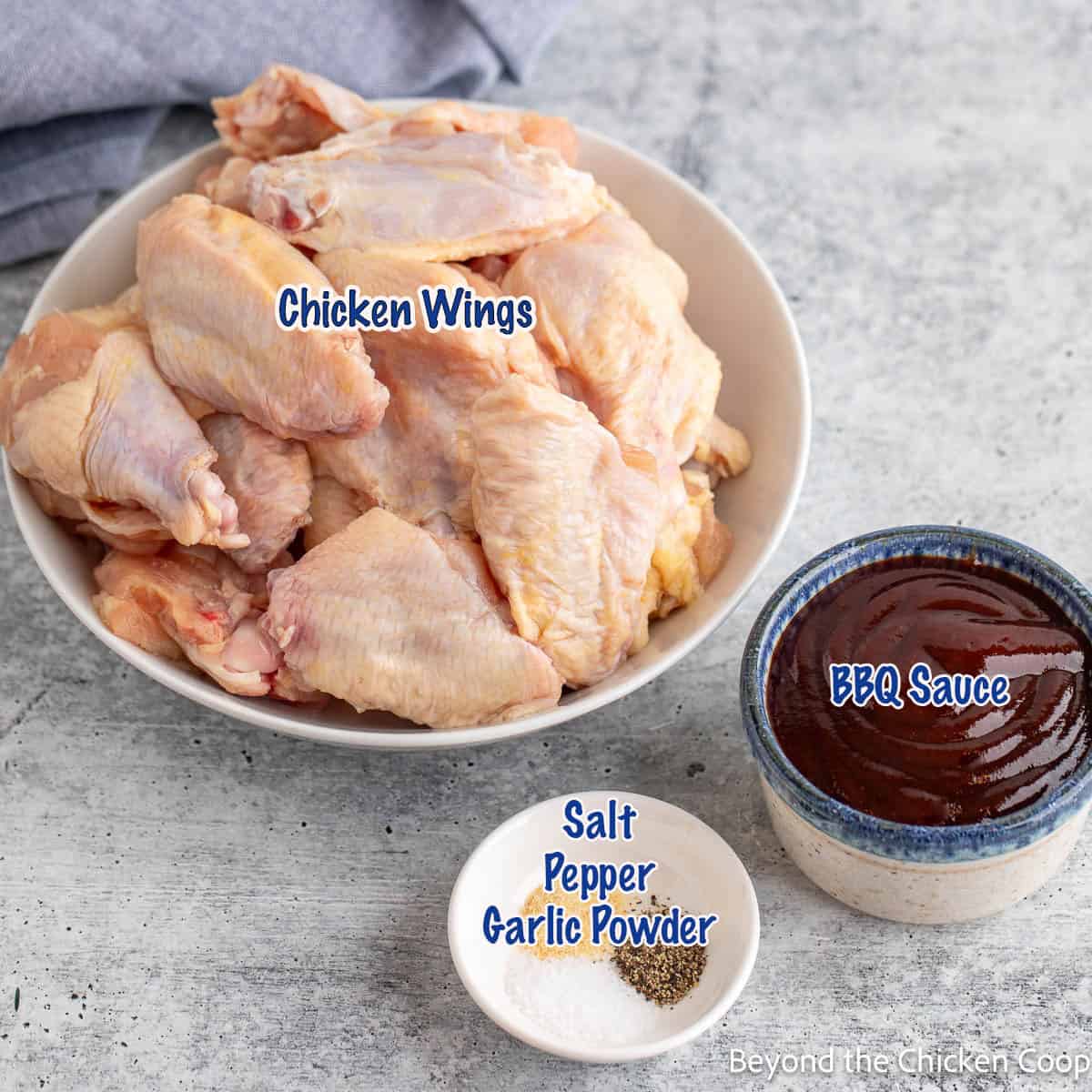 Chicken wings, bbq sauce and seasonings in small bowls. 