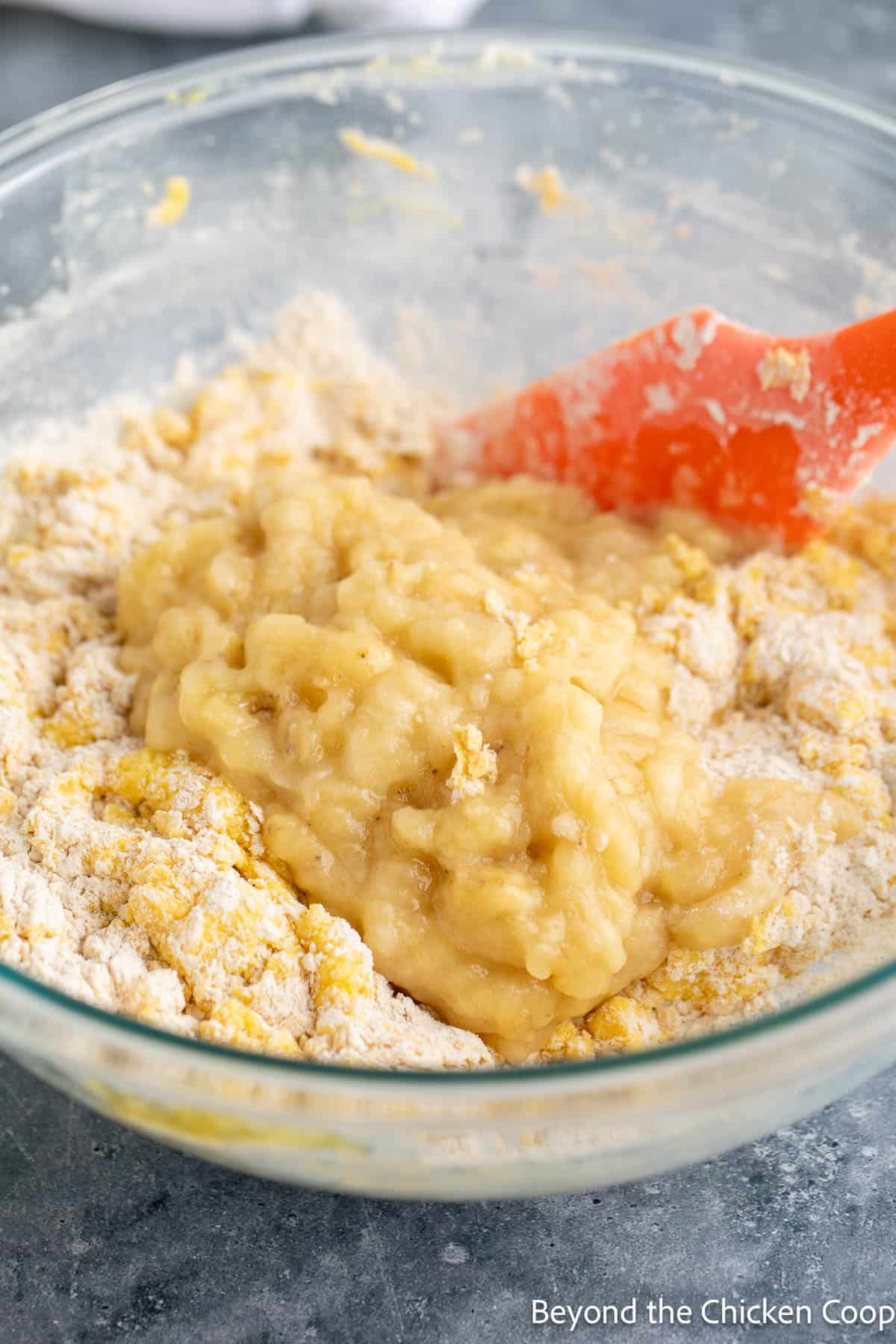 Adding mashed bananas to batter. 