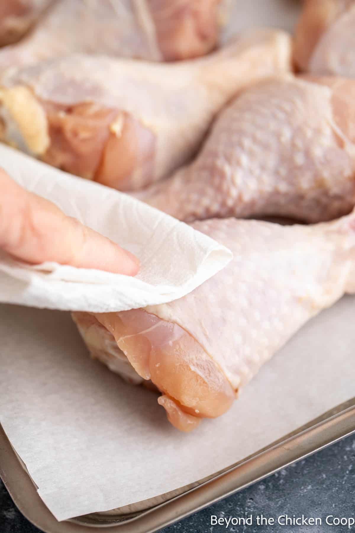 Patting chicken dry with a paper towel. 