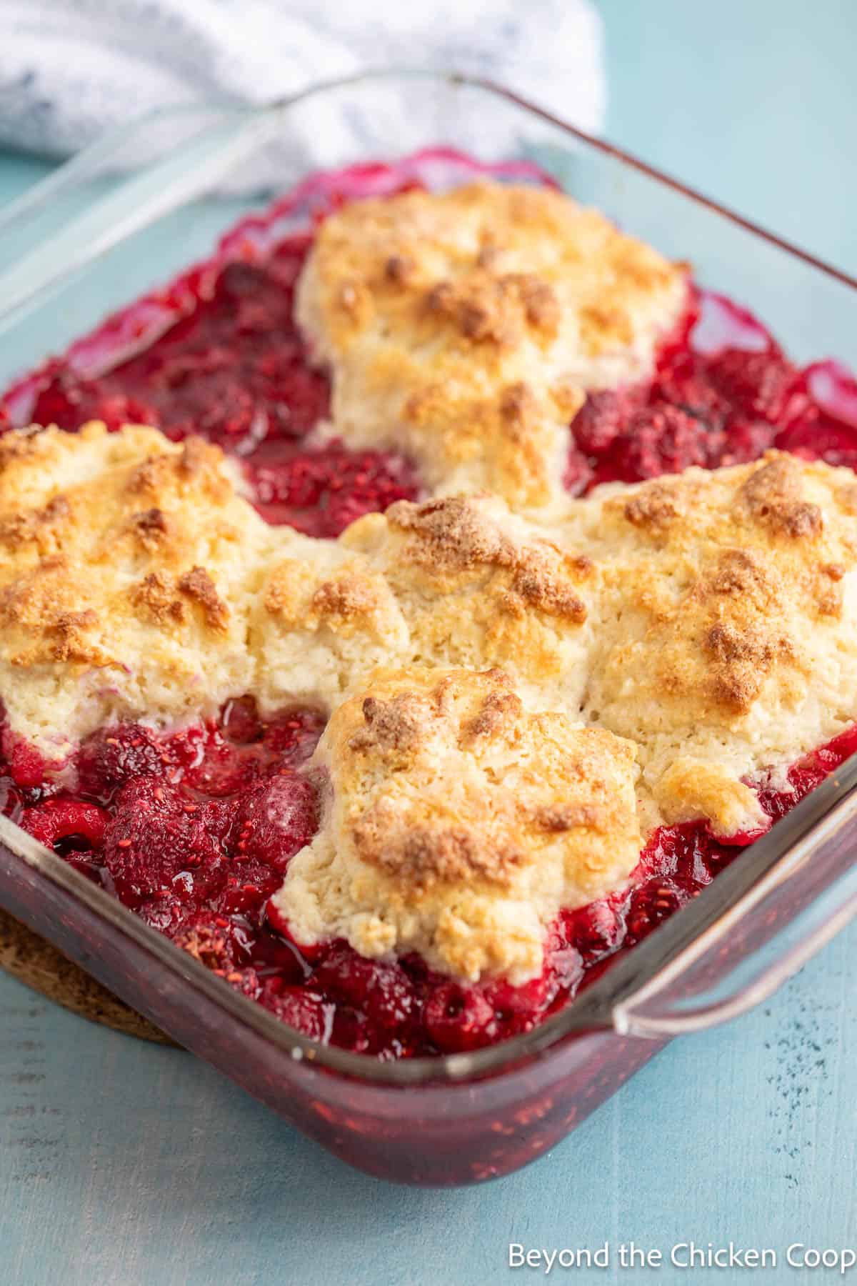 Baked raspberry cobbler in a square casserole dish. 