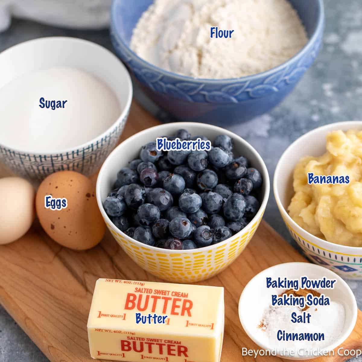Bowls filled with blueberries, mashed bananas, flour and sugar.