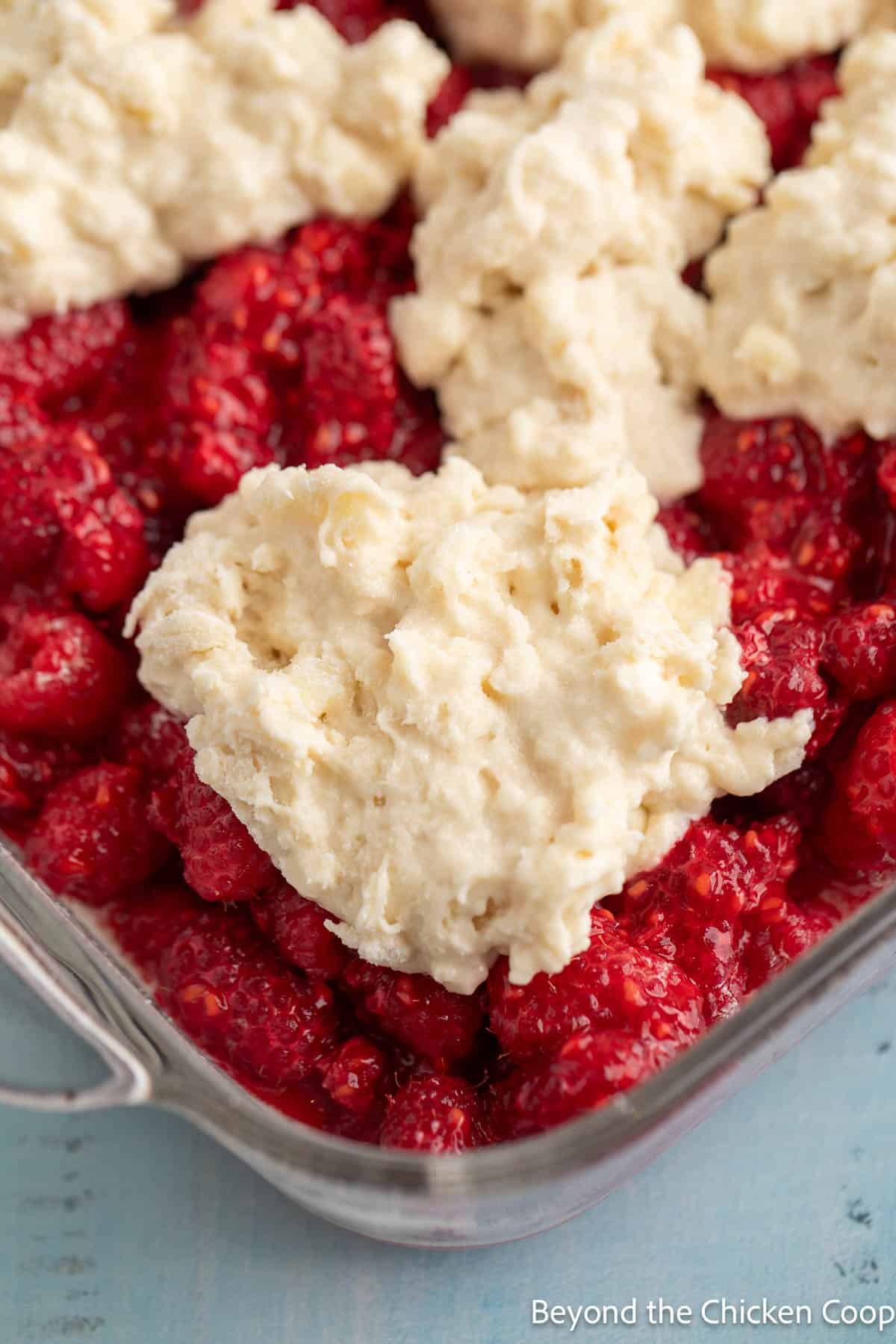 Spooned cobbler topping on raspberries. 