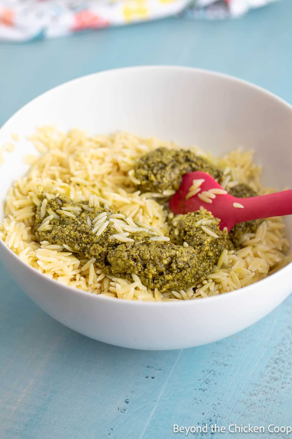 Adding basil pesto to orzo pasta. 