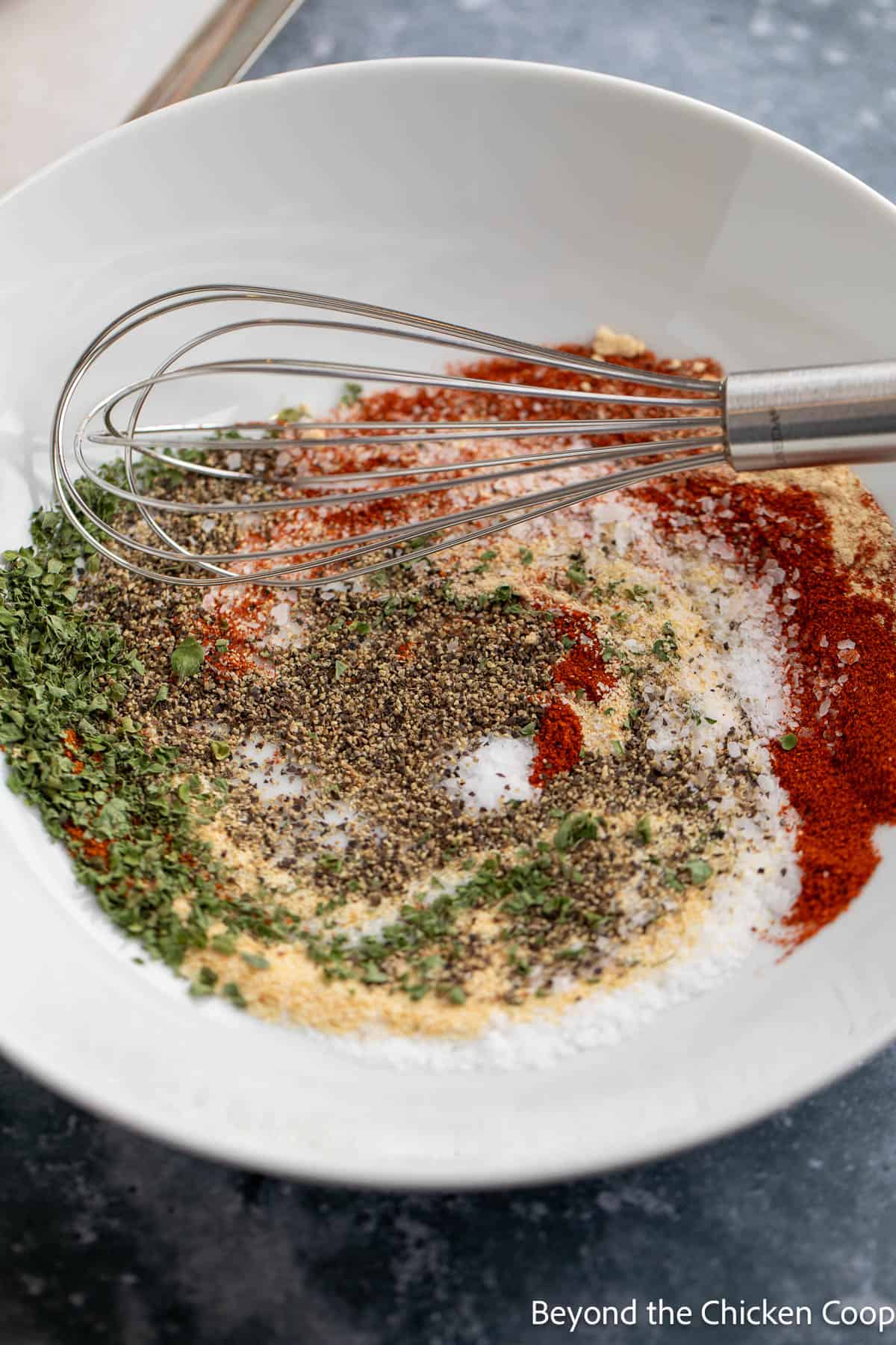 Mixing spices together in a bowl with a whisk. 