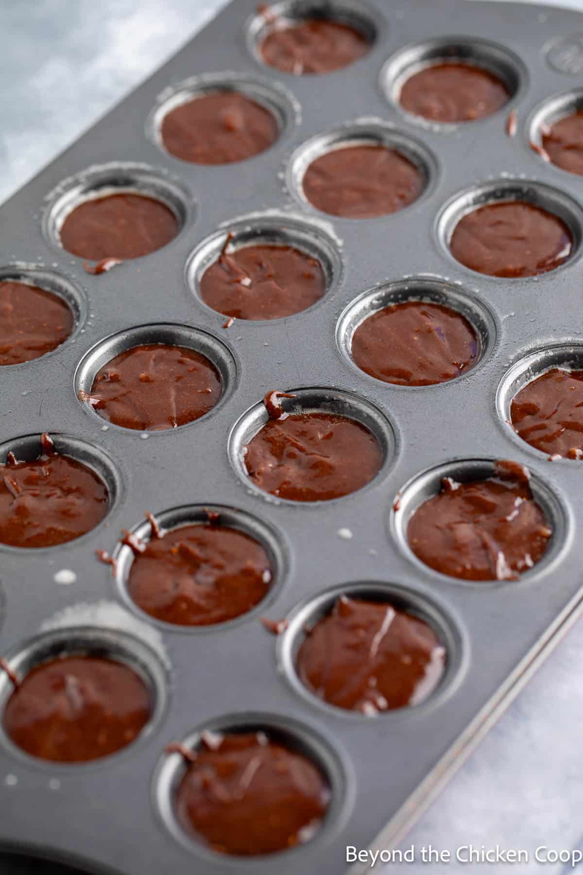 Brownie batter in a mini muffin tin. 