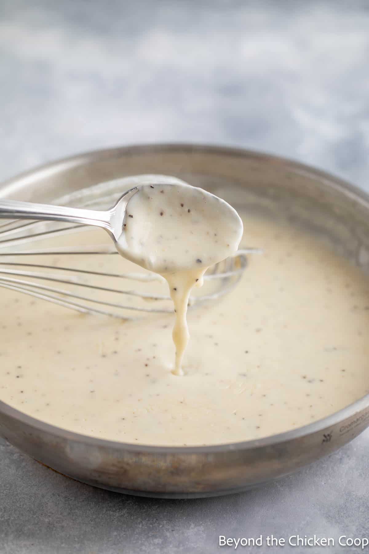 Testing the consistency of white gravy with a spoon. 