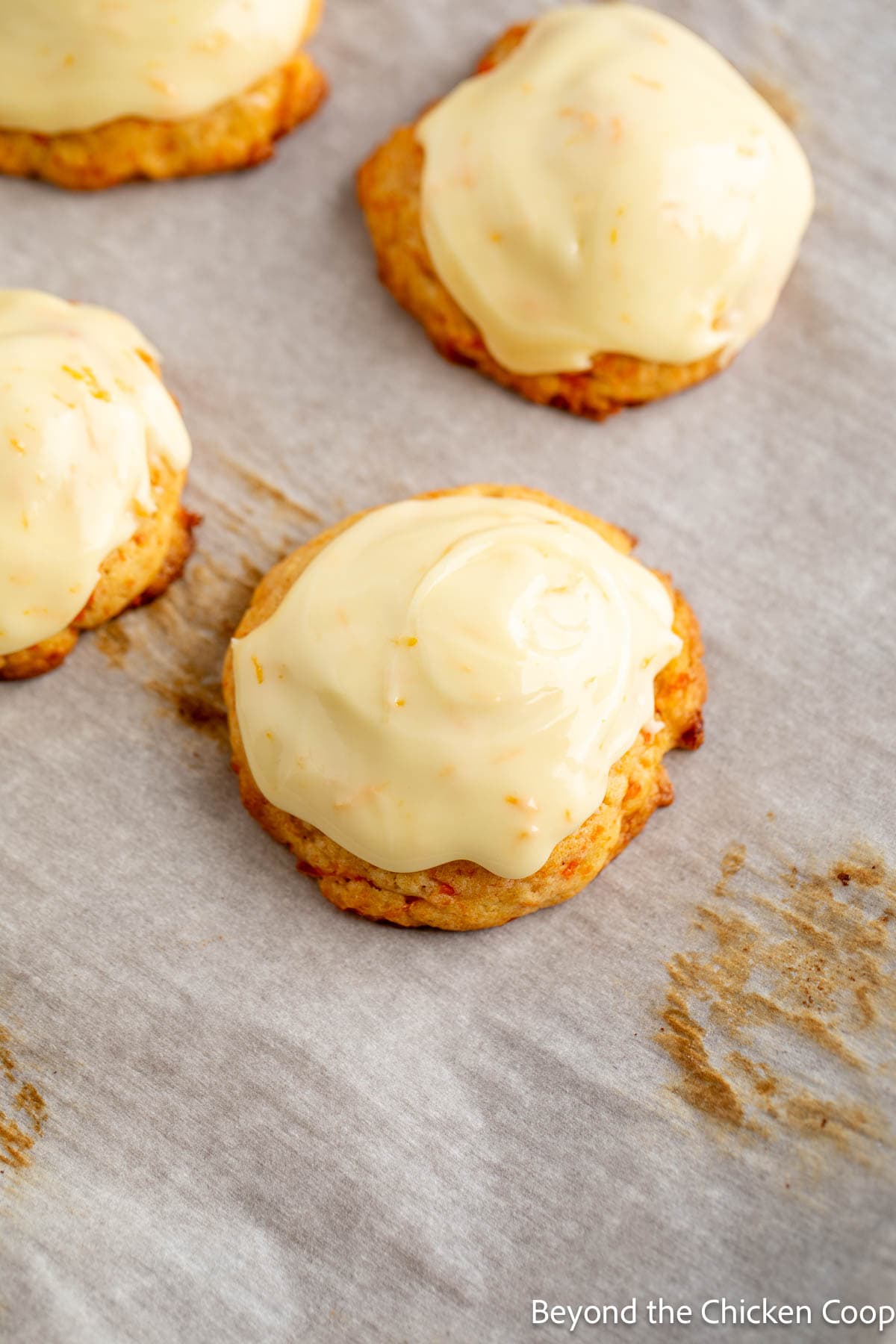Frosted carrot cookies on a baking sheet. 