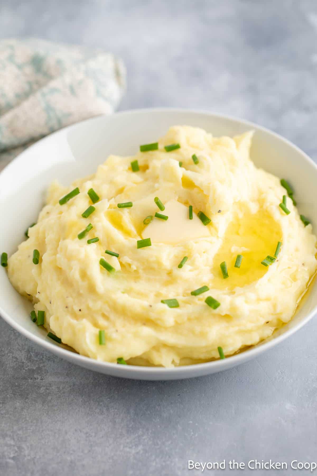 A bowl filled with Yukon mashed potatoes topped with butter and chives. 