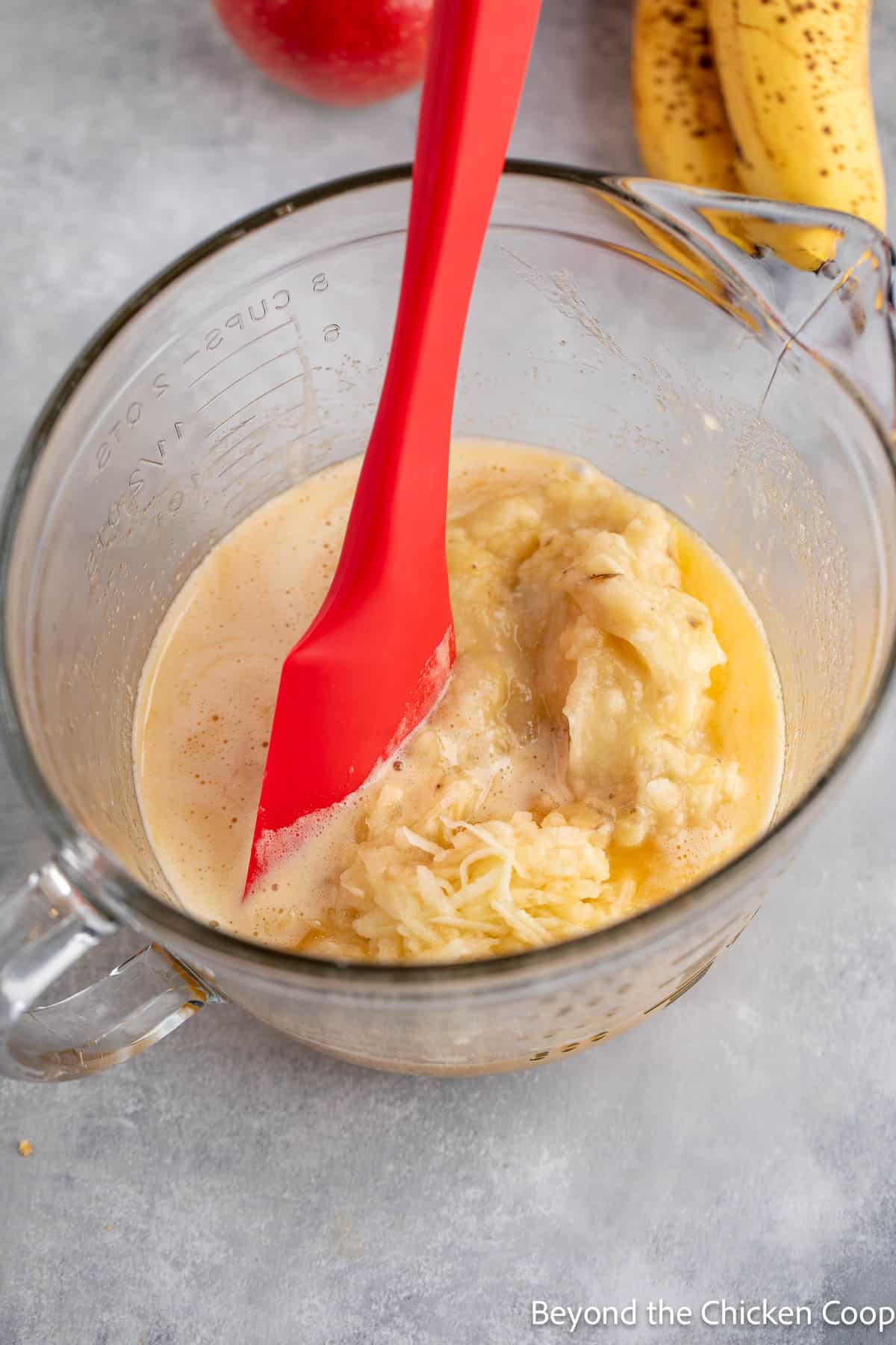 Adding mashed bananas and shredded apples to a batter. 