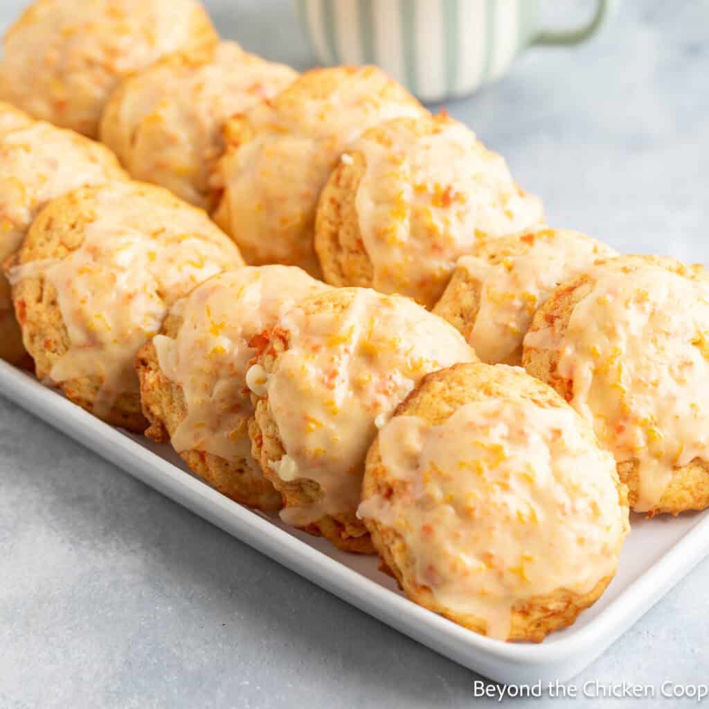 A tray of carrot cookies next to a cup of coffee.