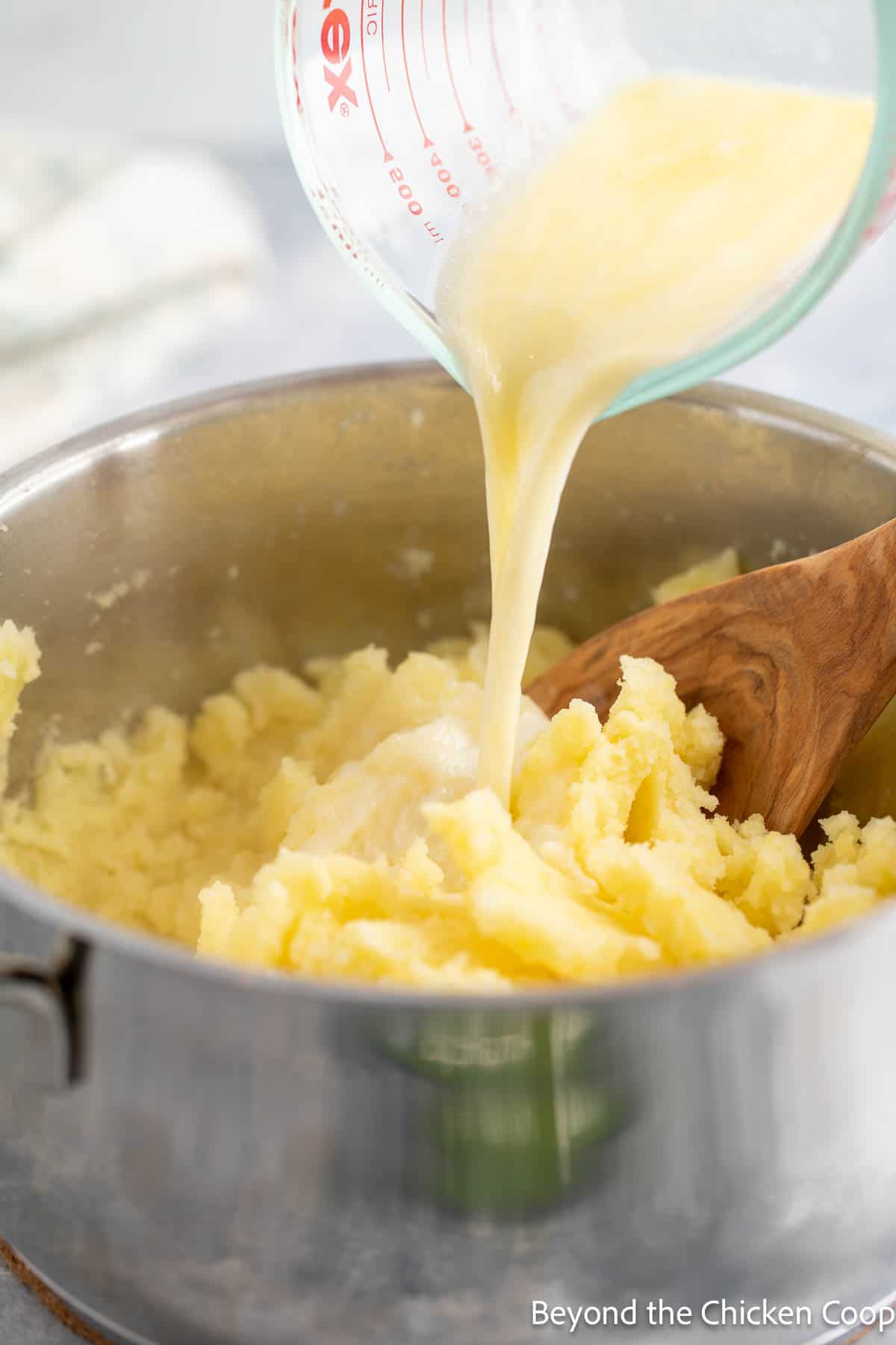 Adding milk to mashed potatoes. 