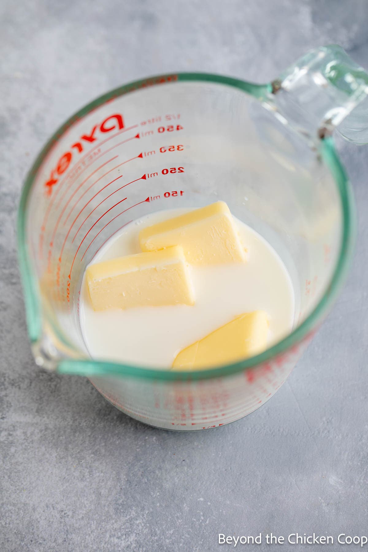 Milk and butter cubes in a glass measuring cup. 