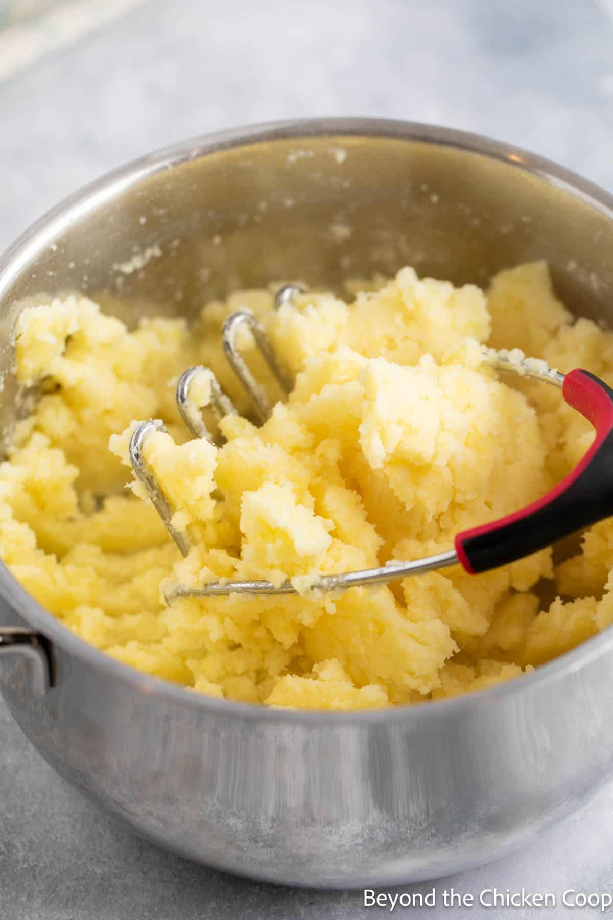 Mashing potatoes in a pot. 