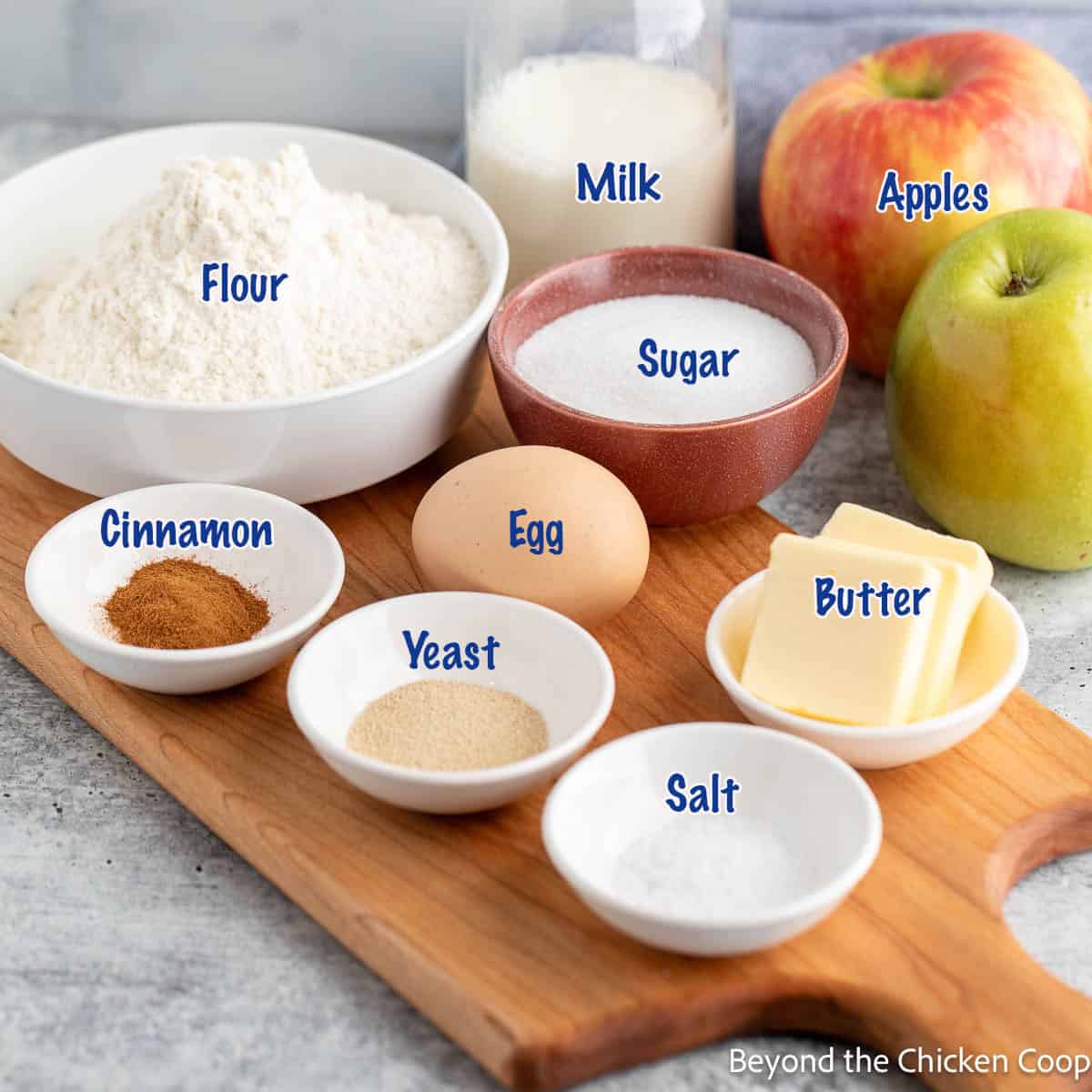 Small bowls filled with ingredients for making bread with an apple filling. 